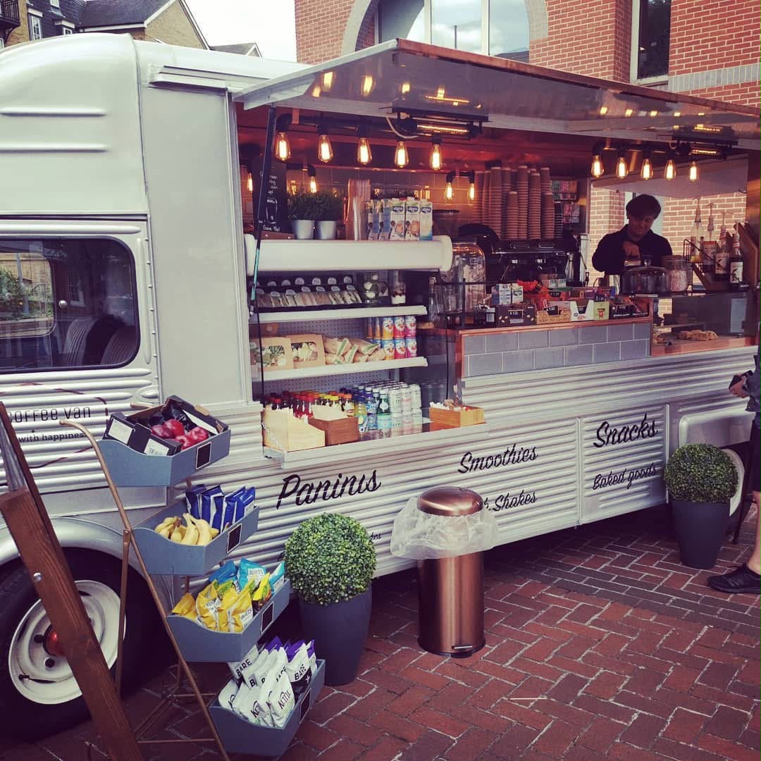 Cream vintage coffee van open for service on a brick plaza